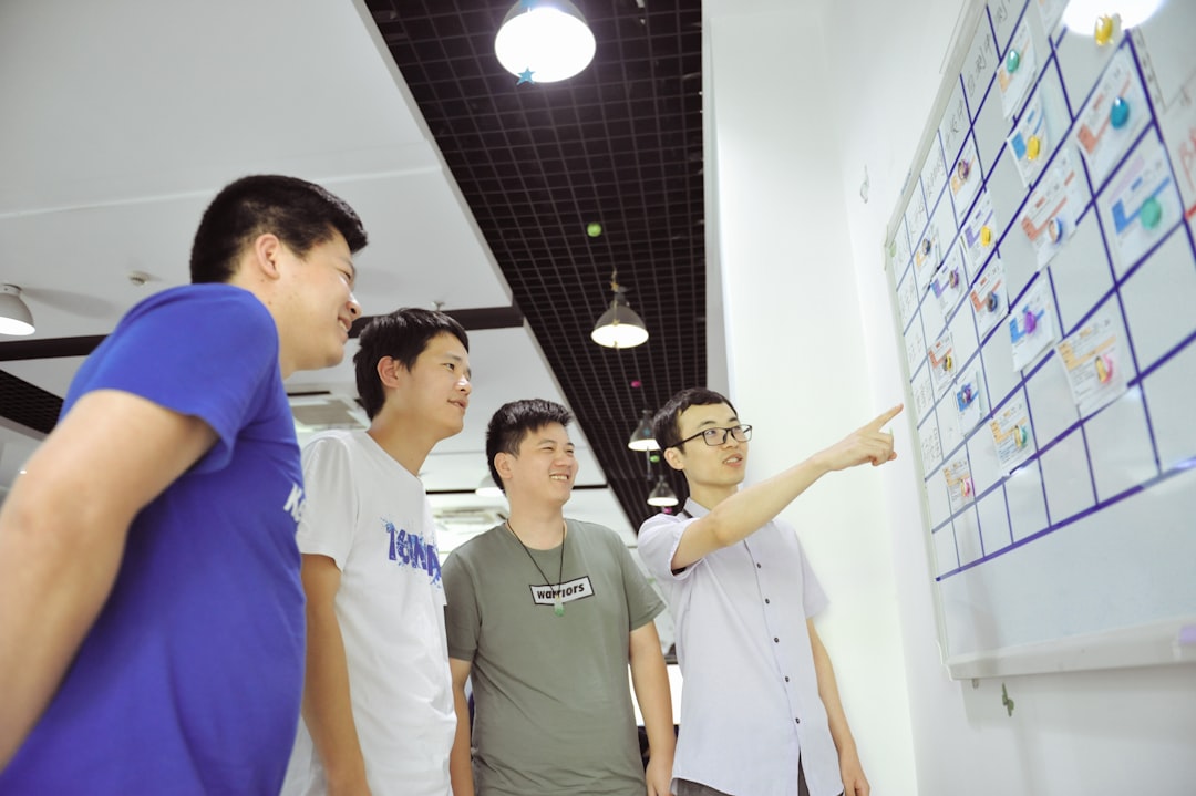 four-men-gathered-around-a-whiteboard-with-sticky-notes-mlwk6ffwuru