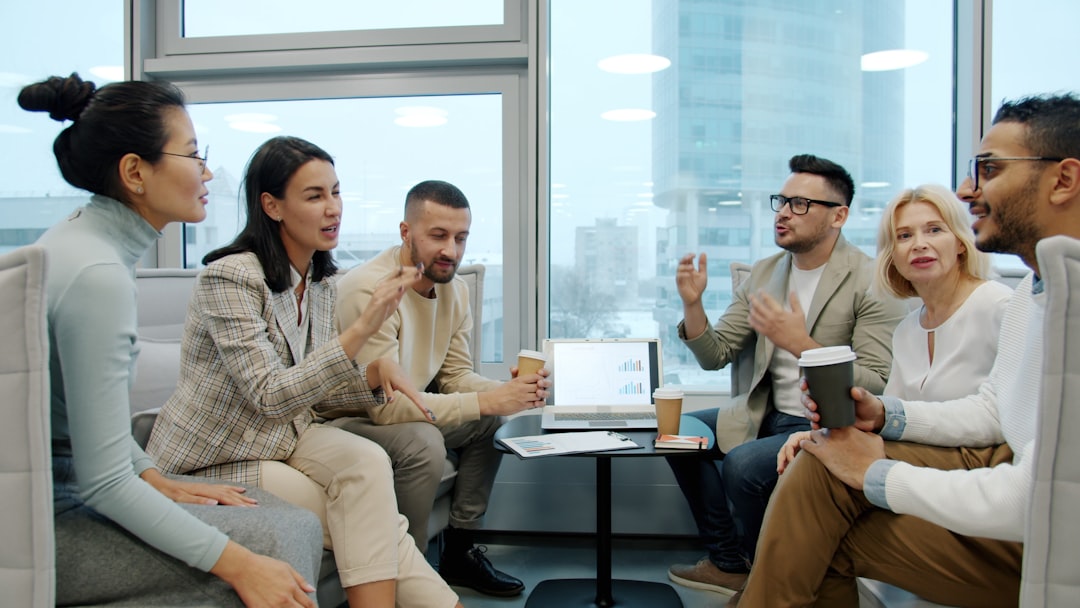 Multiracial group of people women and men are talking discussing work brainstorming in shared office with take out coffee. Communication and business concept.